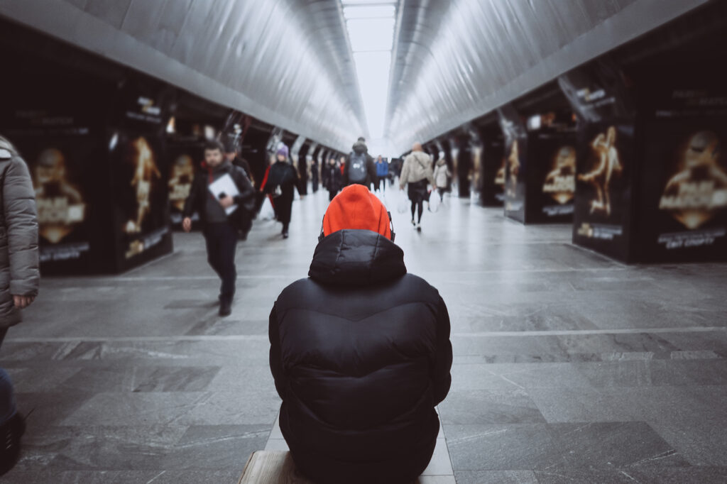 Mężczyzna siedzi na stacji w metrze, słuchając muzyki i starając się zagłuszyć lęk społeczny.